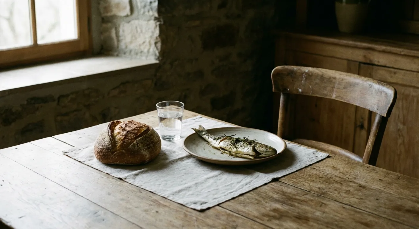 Simple meal of bread and fish on a wooden table with a linen cloth
