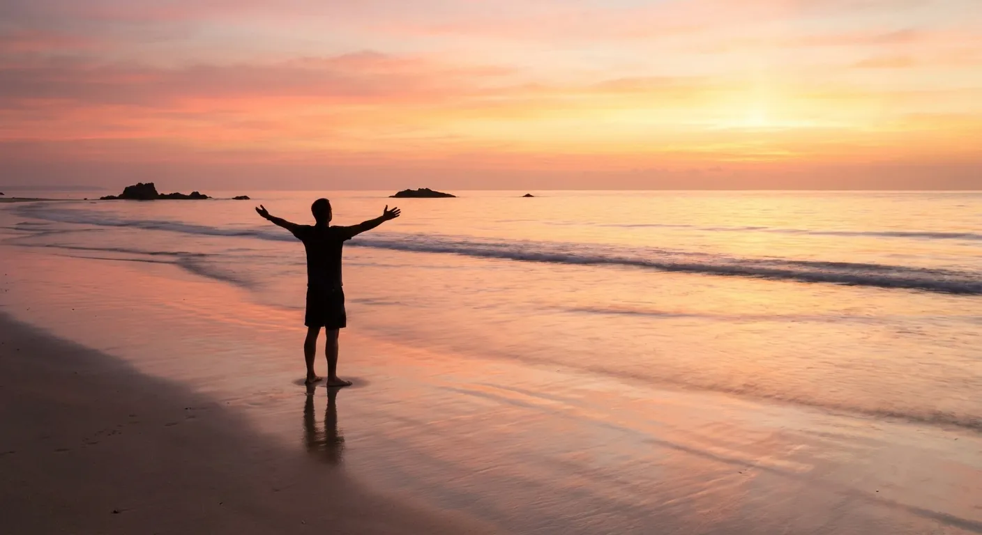 Person standing at ocean's edge at sunrise with arms slightly raised, expressing openness